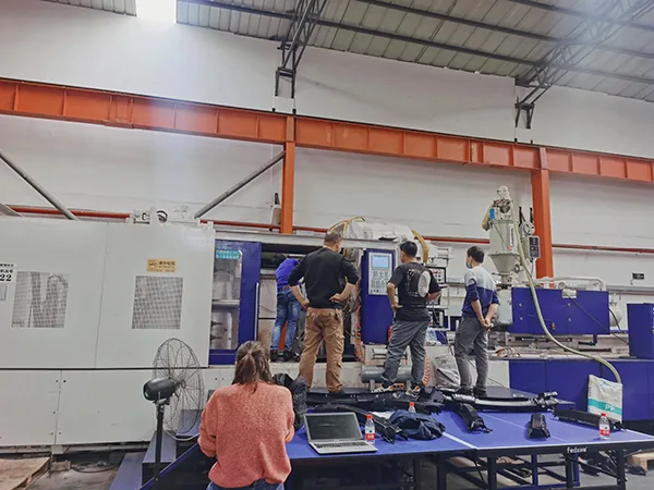 Team reviewing an injection molding machine in the Dongguan New Oriental trial workshop